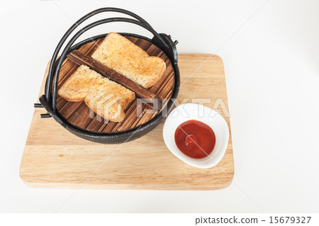 Toast on black iron bowl and tomato sauce on wood 15679327
