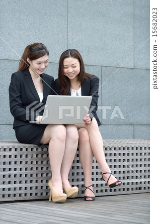 2 Chinese woman using laptop outdoors 15682023
