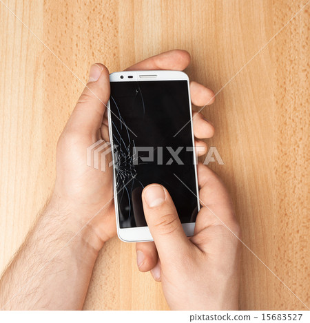 Hands holding a phone with a broken screen Hands holding a phone with a broken screen 15683527