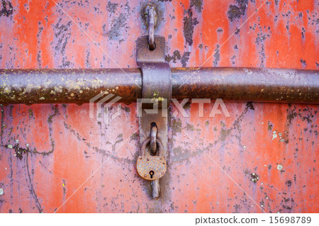 Old rusted padlock on red metal door 15698789