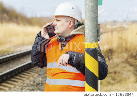 Railway employee talking on cell phone near railwa 15698844