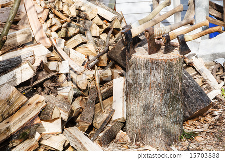 pile of firewoods and several axes in wooden block 15703888