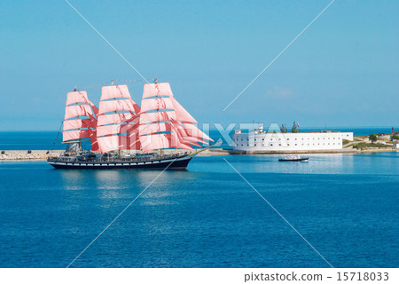 Sailing ship with red sails entering to the bay. 15718033