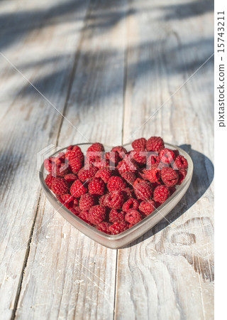 Raspberries in a bowl on wood 15743211