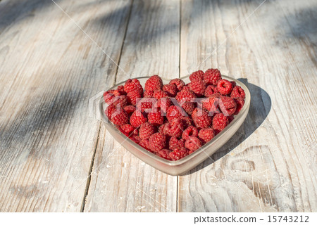Raspberries in a bowl on wood 15743212