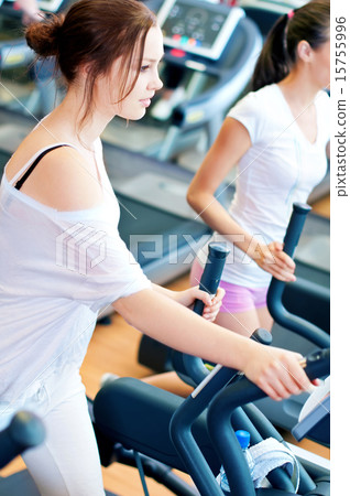 Two young sporty women run on machine 15755996