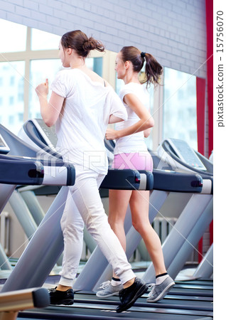 Two young sporty women run on machine 15756070