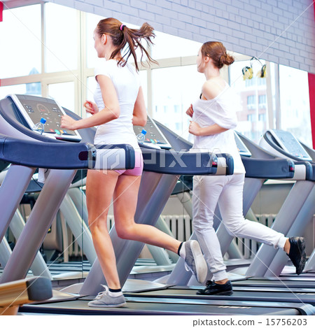 Two young sporty women run on machine 15756203