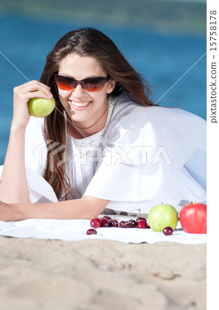 Woman on beach eating fruits 15758178