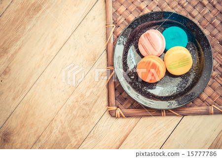 Colorful macaron in black dish on wooden floor Colorful macaron in black dish on wooden floor 15777786