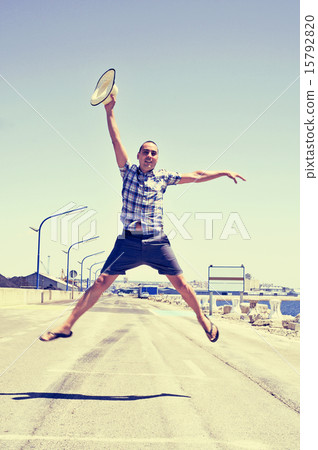 young man jumping with a straw hat in his hand young man jumping with a straw hat in his hand 15792820