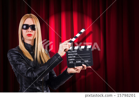 Girl with movie board against curtains Girl with movie board against curtains 15798201
