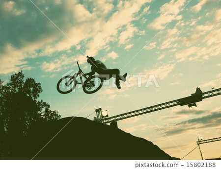Silhouette of a man doing a jump with a bmx bike Silhouette of a man doing a jump with a bmx bike 15802188