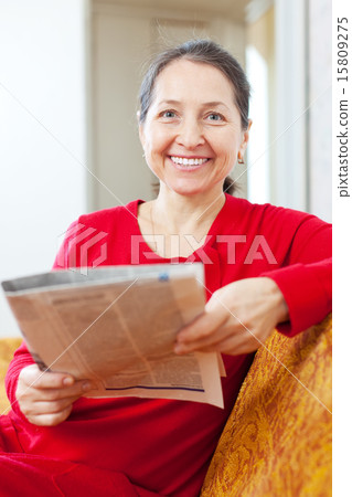 cheerful positive mature woman reads newspaper 15809275