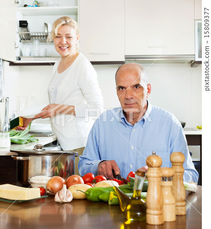 happy senior couple cooking at their kitchen happy senior couple cooking at their kitchen 15809377