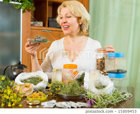 Mature woman with herbs at table 15809453