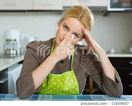 Sad woman sitting at kitchen Sad woman sitting at kitchen 15809607