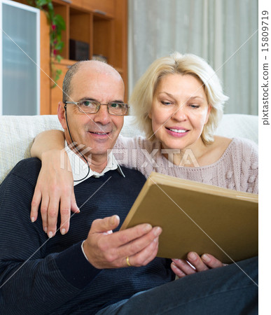 Senior spouses with picture album indoor Senior spouses with picture album indoor 15809719