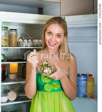 Girl eating salad from fridge 15810346