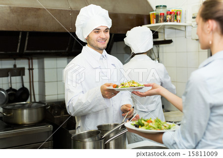 Cook gives to waitress plates Cook gives to waitress plates 15811009