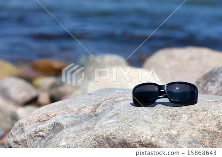Sunglasses lies on a rock on the coast Sunglasses lies on a rock on the coast 15868643