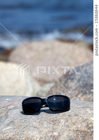 Sunglasses lies on a rock on the coast Sunglasses lies on a rock on the coast 15868644
