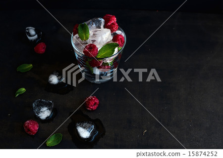 Ice cubes with mint leaves and frozen raspberry in glass on grunge dark background Ice cubes with mint leaves and frozen raspberry in glass on grunge dark background 15874252