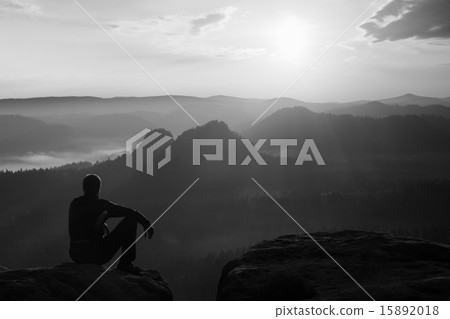 Tourist in black wind jacket sit on sharp rock 15892018