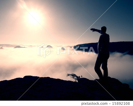 Tall man in jeans is on peak of sandstone empire  15892108