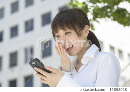 A young lady who is happy to see smartphone outdoors 15898058