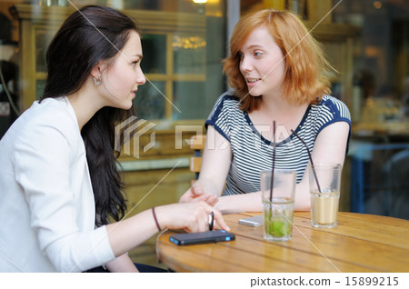Two young woman at the outdoors cafe Two young woman at the outdoors cafe 15899215