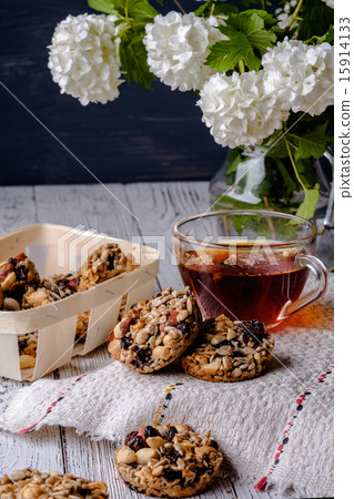 Cup of tea and cookies made of nuts and raisins. 15914133