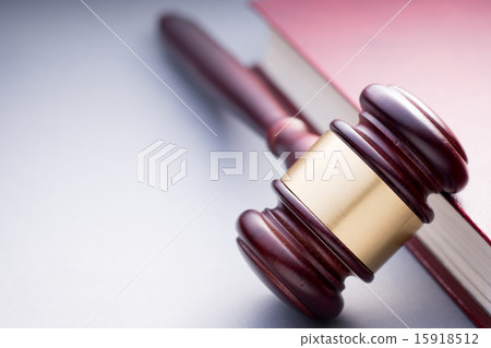 Wooden Gavel Resting on Red Leather Book 15918512