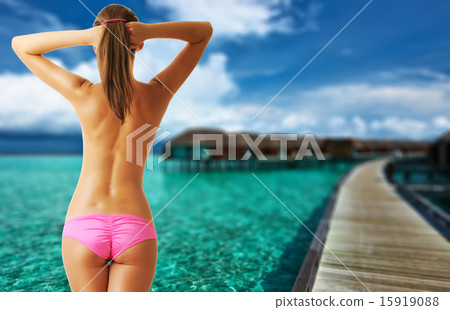 Woman topless on beautiful beach with water bungalows Woman topless on beautiful beach with water bungalows 15919088