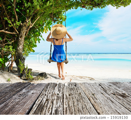 Woman in blue dress swinging at beach 15919130