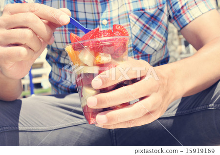 youn man eating a fruit salad outdoors youn man eating a fruit salad outdoors 15919169