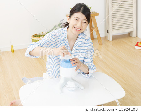A woman shaving ice in a room 15924108