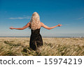 The girl in a black dress standing in the grain field arms sprea 15974219