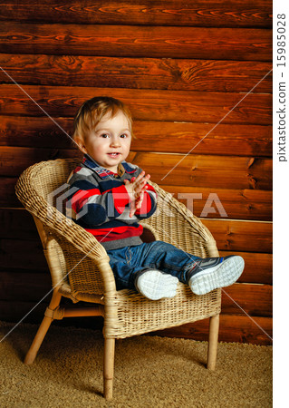 Boy sitting in wicker chair 15985028