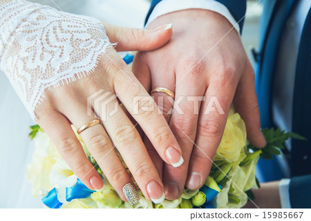 Hands with wedding rings on a bouquet of flowers Hands with wedding rings on a bouquet of flowers 15985667
