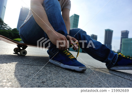skateboarder tying shoelace at skate park skateboarder tying shoelace at skate park 15992689