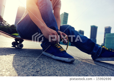 skateboarder tying shoelace at skate park 15992690