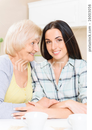 Grandmother and granddaughter sitting in kitchen 16003056