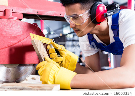 Carpenter in Asian workshop with circular saw 16003334