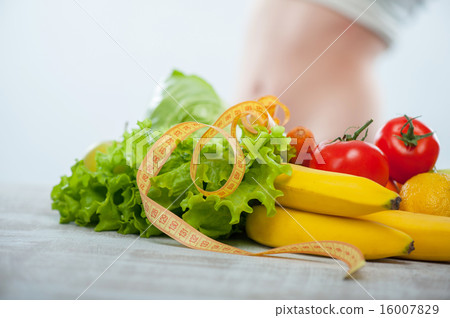 Fit girl is standing behind fruits and vegetables 16007829