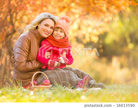 Happy mother and child sitting outdoor in autumn Happy mother and child sitting outdoor in autumn 16013590