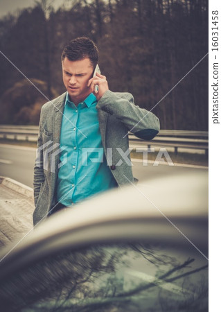 Man calling while tow truck picking up his broken car 16031458
