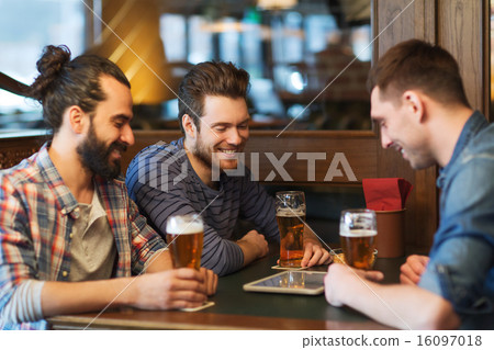 male friends with tablet pc drinking beer at bar 16097018