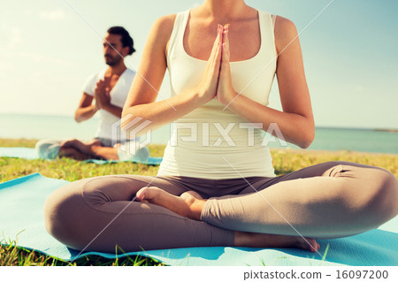 close up of couple making yoga exercises outdoors 16097200