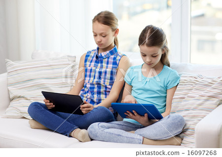 girls with tablet pc sitting on sofa at home girls with tablet pc sitting on sofa at home 16097268